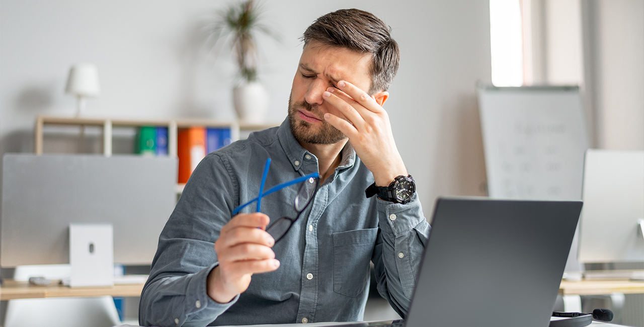 Tired mature man feeling pain eye strain, rubbing dry irritated eyes, fatigued from computer work, sitting in office